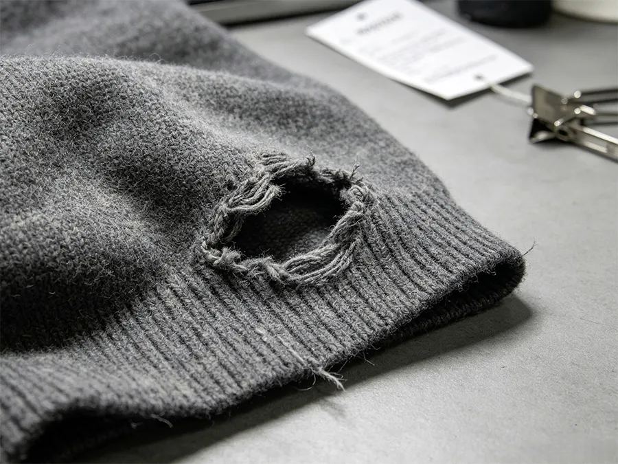 distressed knitwear detail showing controlled hole and ribbed edge finish