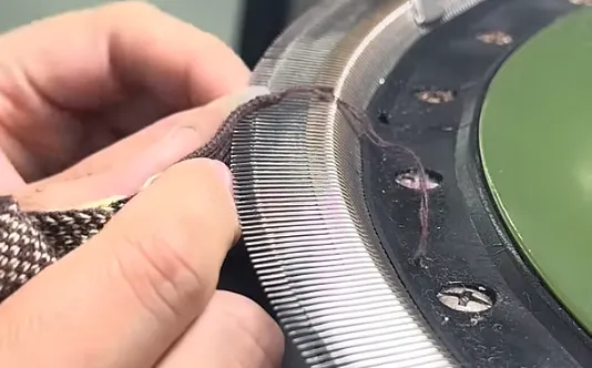 Loop-by-loop hand-linking sweater assembly with embedded Mobilon tape structural reinforcement